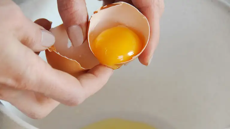 en person slår et æg ud i en skål