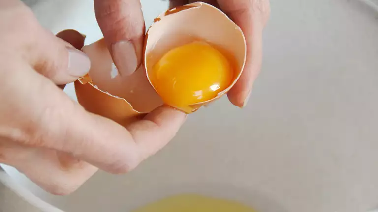 en person slår et æg ud i en skål
