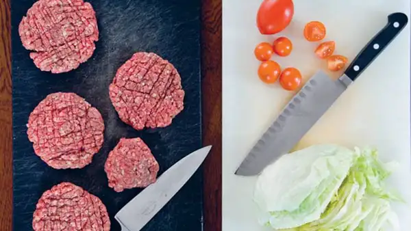 et skærebræt og en kniv med hakket kød - og et andet skærebræt med en anden kniv til salat og tomater