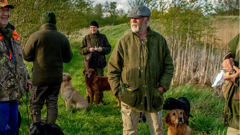 en gruppe jægere holder pause mede deres hunde