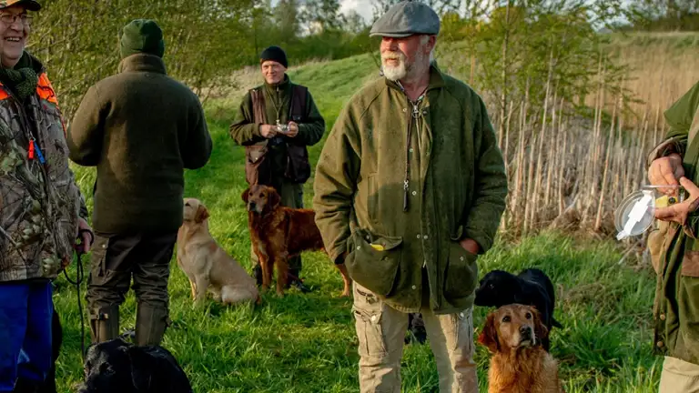 en gruppe jægere holder pause mede deres hunde