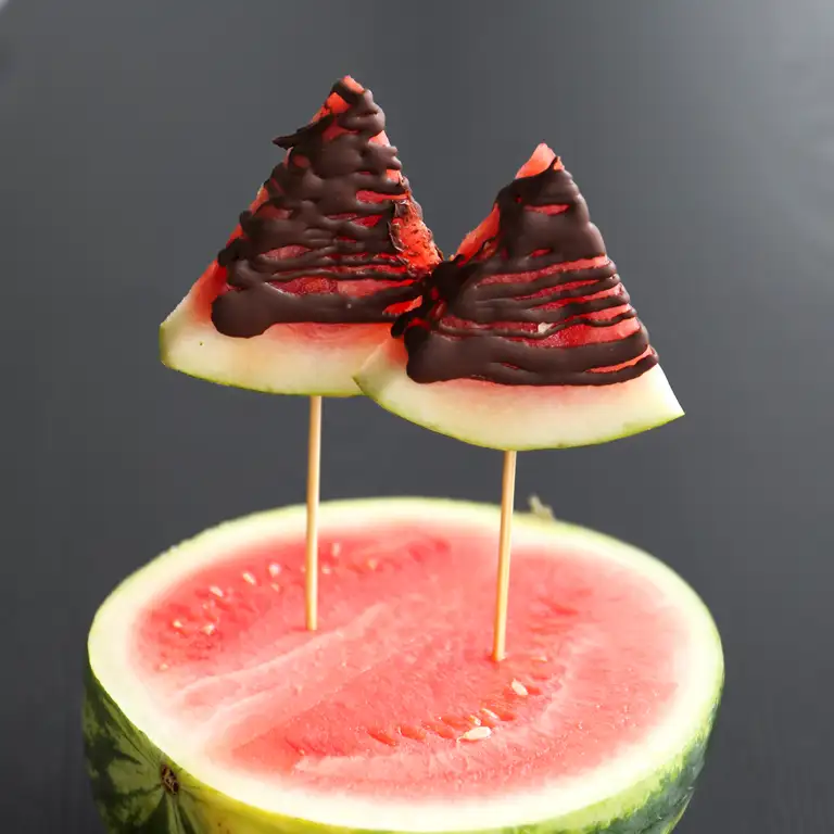 to stykker vandmelon med smeltet chokolade stukket ned i halv vandmelon 