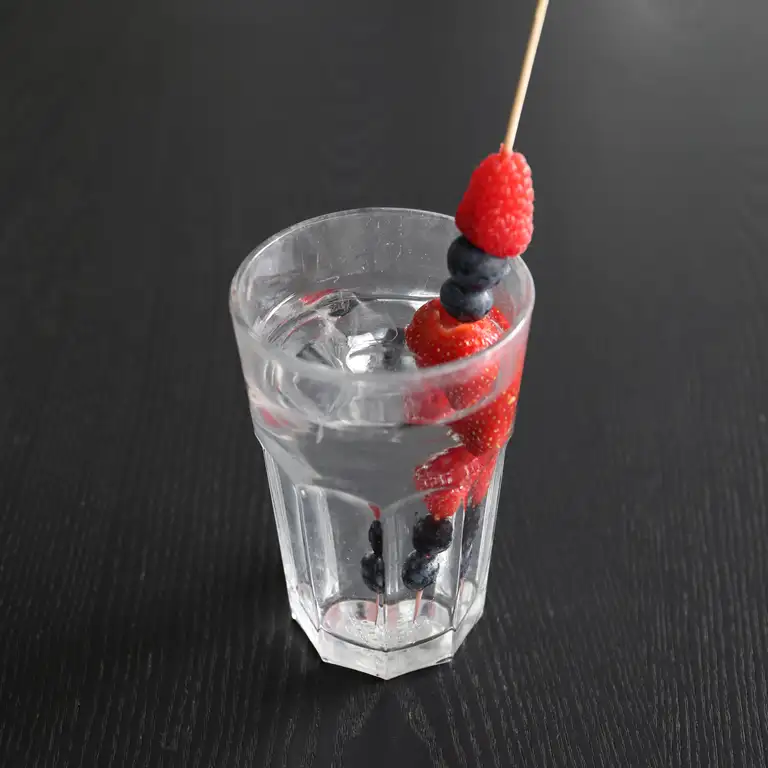 vandglas med blåbær og hindbær på spyd